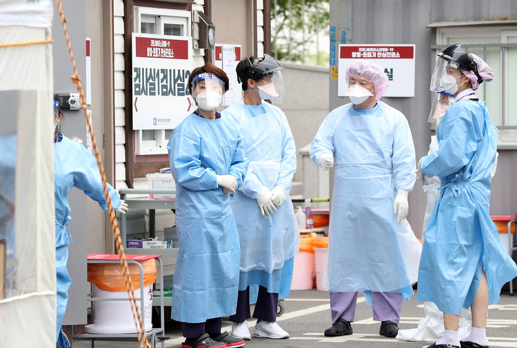  신종 코로나바이러스 감염증(코로나19)의 집단감염이 확산되고 무더운 날씨가 계속되는 가운데 12일 오후 인천시 부평구 가톨릭대학교 인천성모병원 선별진료소에서 의료진들이 레벨D 방호복보다 얇고 통풍이 잘 되는 수술용 1회용 가운을 착용하고 의견을 나누고 있다. 뉴시스 제공