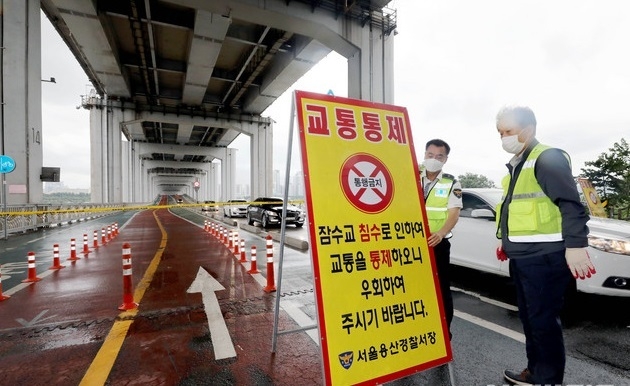 중부지방에 집중호우가 내리는 2일 오후 서울 용산구 잠수교에서 교통경찰이 보행자와 자전거 통행을 제한하는 안내판을 설치하고 있다.