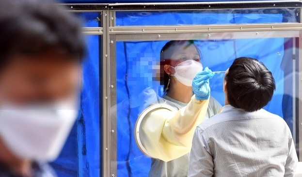 부산기계공고 2학년 학생 3명이 신종 코로나바이러스 감염증(코로나19) 확진 판정을 받은 가운데 13일 오후 해운대구 해당 학교에 마련된 선별진료소에서 한 교직원이 진단검사를 위한 검체를 채취하고 있다.