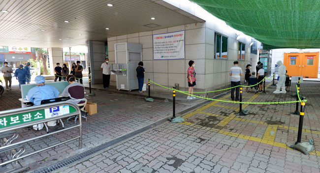지난달 29일 대구 북구 소재 동우빌딩 지하1층에서 열린 동충하초 사업설명회가 코로나19 확산지로 지목되고 있는 가운데 4일 오전 대구 북구 침산동 북구보건소에 마련된 코로나19 선별진료소를 찾은 시민들이 검사를 받기 위해 줄을 서 있다. / 사진제공=뉴시스