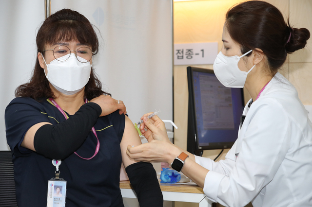 사진공동취재단 = 27일 오전 서울시 중구 을지로 국립중앙의료원 중앙예방접종센터에서 화이자 백신 1호 접종을 받은 환경미화원 정미경 씨가 접종을 받고 있다. 