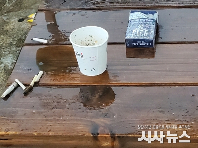 담배꽁초와 빈 담뱃갑이 뒹구는 울산 동강병원 야외휴게실 테이블.