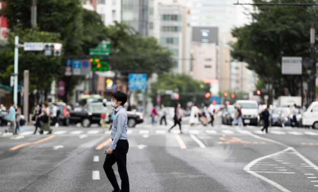 지난달 21일 일본 도쿄의 긴자 쇼핑가에서 코로나19 확산 방지를 위해 마스크를 쓴 한 남성이 길을 건너고 있다. 일본 정부는 21일 미국 모더나 백신과 다국적 제약사의 아스트라제네카 백신을 승인했으며 도쿄 올림픽 개막을 9주 앞두고 코로나19 급증을 막기 위해 긴급 사태를 연장한다고 밝혔다 (사진=뉴시스 제공)