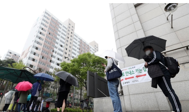 국내 코로나19 신규 확진자 수가 587명으로 집계된 지난 4월 12일 서울 중랑구 보건소에 마련된 코로나19 선별진료소에서 시민들이 우산을 쓰고 대기하고 있다 (사진=뉴시스 제공)