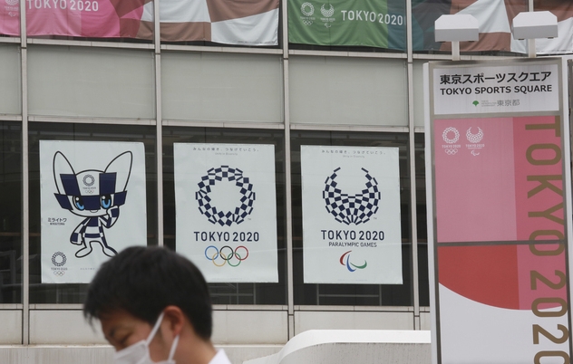지난 7일 도쿄올림픽 홍보 포스터가 내걸린 도쿄 거리를 마스크를 착용한 시민이 지나가고 있다 (사진=뉴시스)