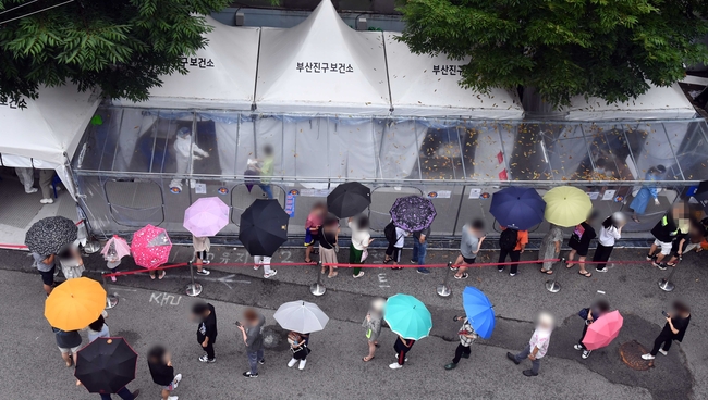 부산 내 코로나19 신규 확진자가 급증하고 있는 가운데 지난 8일 부산진구보건소 선별진료소를 찾은 시민들이 진단검사 검체 채취를 위해 줄을 선 채 차례를 기다리고 있다 (사진=뉴시스 제공)