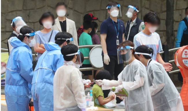 초등학생 코로나19 집단 감염이 발생한 지난 6일 오전 인천 미추홀구 인주초등학교에 마련된 워크스루(Walk Through) 선별 진료소를 찾은 학생과 학부모, 가족들이 검사를 받기 위해 줄을 서고 있다 (사진=뉴시스 제공)