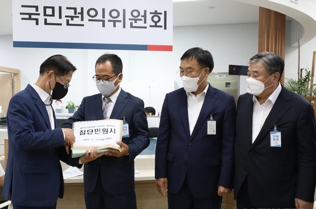 정준화 강원시군번영회 연합회장 및 관계자들이 지난달 30일 오전 서울 종로구 정부서울청사 정부합동민원센터 민원실에서 설악산 오색케이블카 설치사업에 관한 행정심판 인용결정 이행 촉구하는 설악산국립공원 오색삭도 설치작업 집단민원서를 권근상(왼쪽) 정부합동민원센터장 전달하고 있다. (사진=뉴시스 제공)