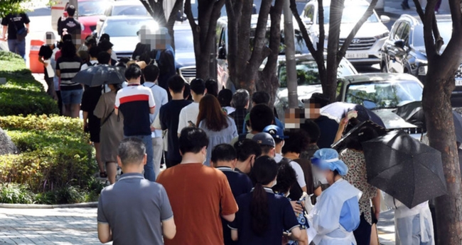 부산지역 코로나19 확산세가 심상치 않은 가운데 지난 26일 오전 부산 남구보건소 선별진료소를 찾은 시민들이 진단검사를 받기 위해 길게 줄을 선 채 차례를 기다리고 있다. 이날 해당 보건소 주변으로 검사 대기 줄이 100m 가량 이어졌다 (사진=뉴시스 제공)