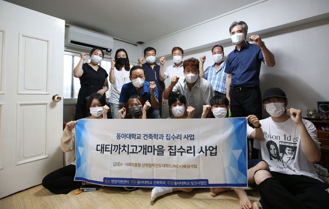 동아대 LINC+사업단과 건축학과가 추진한 부산 사하구 ‘대티까치고개마을 집수리 사업 준공식’에서 이성호(뒷줄 맨 오른쪽) 교수와 학생들, 마을주민 등이 기념촬영을 하고 있다.