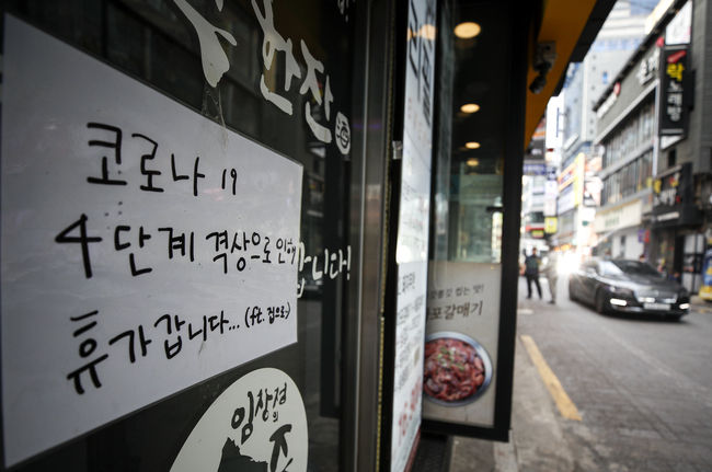 코로나19 확산세가 계속됨에 따라 정부가 수도권 4단계, 비수도권 3단계 거리두기를 2주 연장한다고 발표한 20일 오후 서울 종로구 젊음의거리에 위치한 한 식당에 안내문이 붙어 있다. 정부는 거리두기 연장과 관련해 4단계 지역의 식당과 카페는 영업시간을 밤 10시에서 9시까지 단축하고, 저녁 6시 이후엔 백신 접종 완료자 2명을 포함해 총 4인까지 모일 수 있도록 했다. / 사진제공=뉴시스,