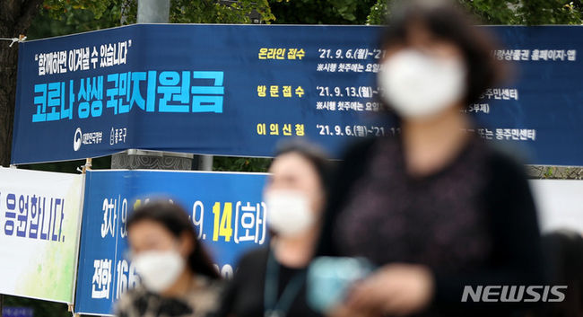 코로나 상생 국민지원금 신청이 시작된 6일 오전 서울 중로구 도심에서 시민들이 '코로나 상생 국민지원금' 신청 안내 현수막 앞을 지나고 있다.(사진=뉴시스 제공)