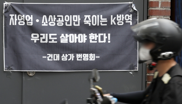 코로나19 4차 대유행의 장기화 속에 본격적인 여름 휴가철이 시작된 3일 오전 서울 광진구 한 상점에 정부의 방역 지침에 항의하는 현수막이 붙어 있다.