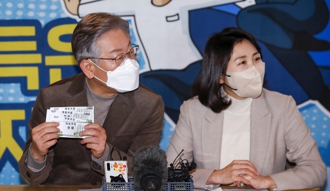 이재명 더불어민주당 대선 후보와 부인 김혜경 씨가 21일 오전 충북 보은군 보은마루에서 열린 판동초등학교 학생들과 함께하는 국민반상회에서 팔판동사회적협동조합에서 발급하는 매점쿠폰을 살펴보고 있다.