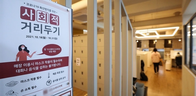 현행 사회적 거리두기 단계가 2주 연장된 지난 10월 18일 오전 서울 시내 스터디카페에 운영시간 변경 안내문이 붙어있다. 수도권을 비롯한 4단계 지역은 시간관계없이 접종 완료자 4~8명을 포함해 최대 8명까지 모일 수 있다. 4단계 지역의 식당·카페 영업 시간은 밤 10시까지 제한되지만 독서실·스터디카페·공연장·영화관 등은 밤 12시까지 운영할 수 있다. (사진=뉴시스 제공)