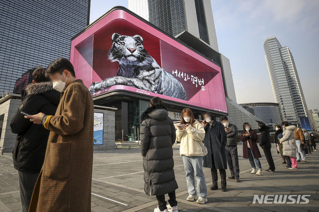 지난 23일 오후 서울 강남구 코엑스 대형 전광판에서 상영중인 2022년 맞이 흑호 미디어아트 앞으로 삼성역 임시선별진료소를 찾은 시민들이 코로나19 검사를 받기 위해 줄 서 있다. (사진=뉴시스 제공)
