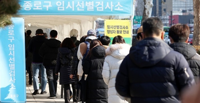 0시 기준 코로나19 신규 확진자가 7,009명으로 집계된 22일 서울 종로구 탑골공원 삼일문 임시선별검사소를 찾은 시민들이 검사를 받기 위해 대기하고 있다.