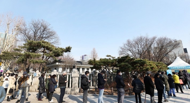 0시 기준 코로나19 신규 확진자가 7,009명으로 집계된 22일 서울 종로구 탑골공원 삼일문 임시선별검사소를 찾은 시민들이 검사를 받기 위해 대기하고 있다.