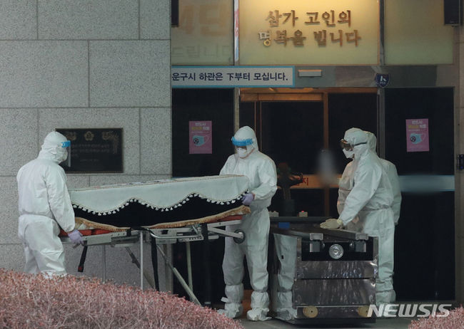 22일 오후 경기도 한 화장장에서 방역 관계자들이 코로나19로 숨진 고인의 관을 화장터로 이송하고 있다. (사진=뉴시스 제공)