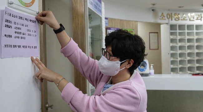  만 5~11세 소아 대상 코로나19 백신 예방접종 사전예약일인 24일 오후 서울 시내 한 소아청소년과의원에서 간호사가 유소아 대상 코로나19 백신 접종 예약 안내문을 부착하고 있다. 접종 시행 위탁의료기관은 총 1200개소가 선정됐으며, 코로나19 예방접종 홈페이지에서 확인할 수 있다.