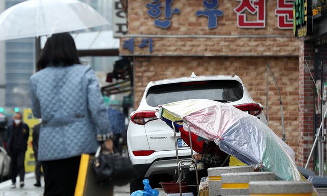 봄비가 내린 지난 달 30일 오후 서울 도심에서 노점상이 파라솔을 쓰고 채소를 판매하고 있다.(사진=뉴시스 제공)
