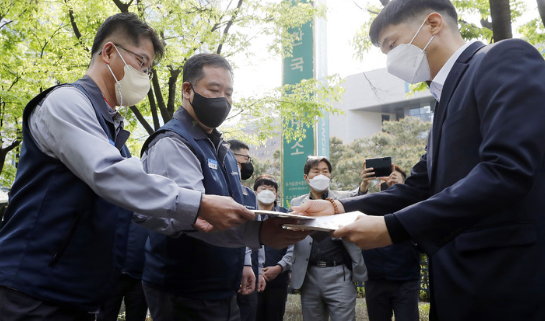 쌍용자동차 노동조합 선목래 위원장을 비롯한 노조원들이 21일 서울 영등포구 한국거래소 앞에서 상장폐지 사유 해소를 위한 개선기간 연장을 호소하는 청원서, 탄원서를 한국거래소 관계자에게 전달하고 있다.(사진=뉴시스 제공)