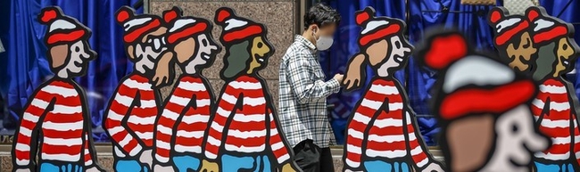 정부가 내달 2일부터 실외 마스크 의무 착용 해제를 발표한 29일 오후 서울 강남구 삼성역 인근에서 마스크를 쓴 시민들이 마스크가 없는 캐릭터 사이로 지나가고 있다.