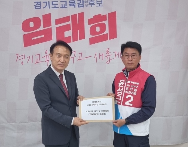 윤성근<오른쪽> 후보가 임태희 경기도교육감 후보에게 평택중학교 용죽지구로 신설 대체 이전 조기 추진 등이 담긴 교육 공약을 전달하고 있다.