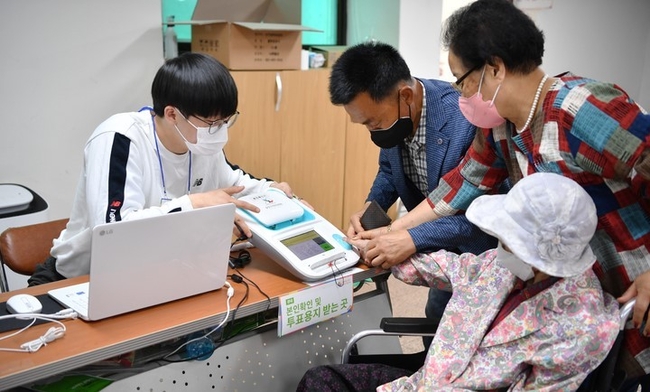 6·1 지방선거 사전투표가 진행된 28일 오전 광주 지역 최고령 유권자인 박명순(118) 여사가 북구 문흥1동 행정복지센터에 마련된 사전투표소를 찾아 신분을 확인하고 있다.