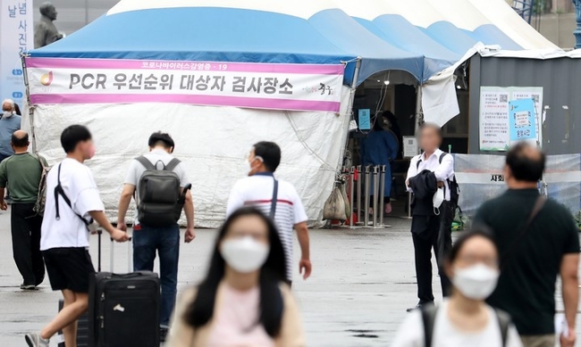 코로나19 신규 확진자가 1만463명으로 집계된 지난달 29일 오전 서울 중구 서울역에 마련된 임시선별검사소 앞을 시민들이 오가고 있다.