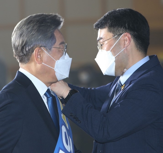  12일 오후 이재명 더불어민주당 대선 경선 후보의 수행비서인 김남국 의원이 강원도 원주시 오크밸리 리조트 컨벤션홀에서 열린 제20대 대통령선거 후보자 선출을 위한 합동연설회에 행사장에서 어깨띠를 걸어주고 있다. 
