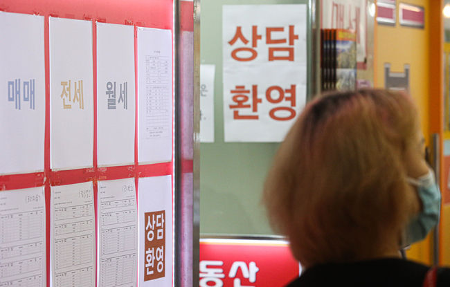 한 시민이 부동산 업체 앞에서 월세 공고문을 유심히 살펴보고 있다. 