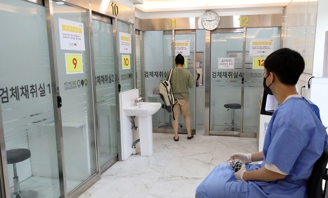 코로나19 신규 확진자가 2만410명으로 집계된 10일 오전 서울 강남구보건소 선별진료소에서 한 시민이 검사를 받기 위해 채취실로 들어가고 있다.