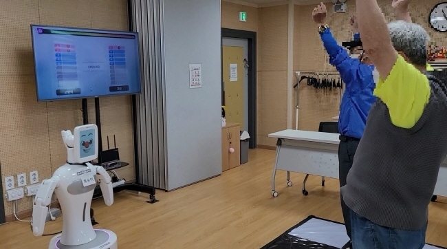 치매 어르신들이 천안시 치매안심센터에서 AI 로봇 똑순이와 쉼터학교 프로그램에 참여하고 있다.(사진=천안시 제공)