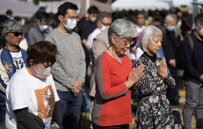 지난 11일 일본 도쿄 히비야 공원에서 시민들이 12년 전의 3·11 동일본대지진 참사를 추모하기 위해 1분간 묵념하고 있다. 코로나19 감염 예방을 위해 마스크를 착용한 시민도, 착용하지 않은 시민의 모습도 함께 보인다. (사진=뉴시스 제공)