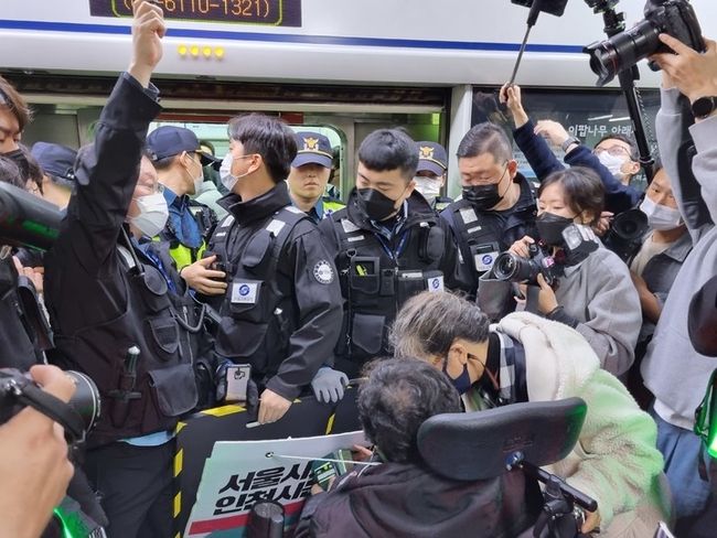 전국장애인차별철폐연대(전장연)가 23일 출근길 서울 지하철 1호선 시청역에서 지하철 탑승을 시도했지만, 이를 저지하는 경찰과 지하철 보안관에 막혀 대치 중이다.(사진=뉴시스 제공)
