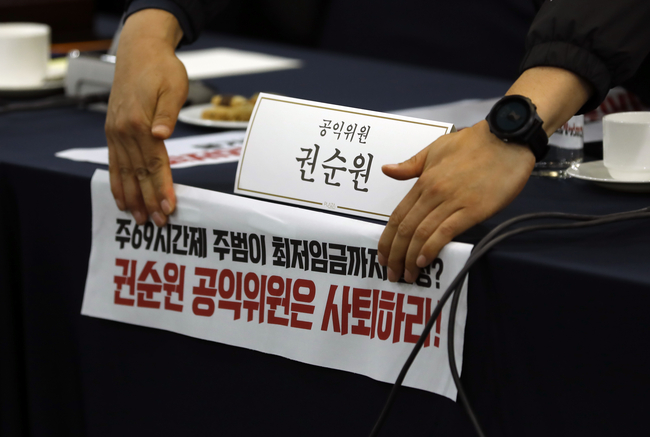 18일 서울 프레스센터에서 최저임금위원회 제1차 전원회의를 앞두고 양대노총 관계자들이 권순원 공익위원 자리에 피켓을 붙이고 있다.(사진=뉴시스 제공)