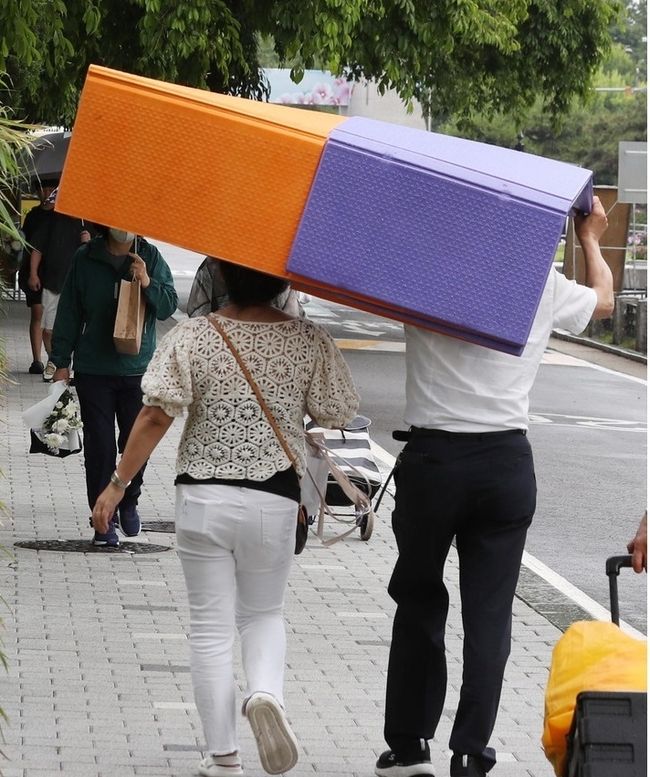  현충일인 지난 6일 오후 서울 동작구 국립서울현충원에서 소나기가 내리자 시민들이 돗자리를 머리에 쓰고 비를 피하고 있다.(사진=뉴시스 제공)