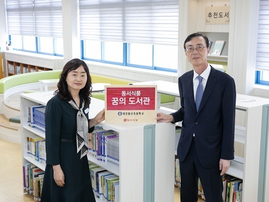  2일 대전광역시 서구에 위치한 대전봉산초등학교에서 진행된 '2024 동서식품 꿈의 도서관‘ 도서 기증식에서 동서식품 최상인 홍보상무(오른쪽)와 대전봉산초 김미애 교장(왼쪽)이 현판과 함께 기념사진을 촬영하고 있다. (사진=동서식품 제공)