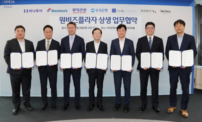 우리은행이 서울 중구 소재 우리은행 본점에서 원비즈플라자 상생 업무협약식을 진행했다. (왼쪽부터) 하나투어 이대훈 상무, 도미노피자 김영훈 사장, 롯데관광 백현 대표이사, 우리은행 조병규 은행장, 나이스디앤비 오유근 대표이사, 모나용평 김진수 부사장, 특허법인다나 진희동 대표 변리사가 협약식 이후 기념사진을 촬영하고 있다. (사진=우리은행 제공)