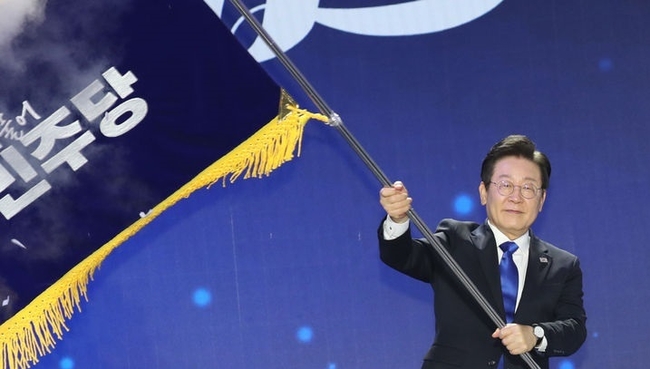 연임에 성공한 이재명 더불어민주당 신임 대표가 18일 서울 송파구 KSPO DOME(올림픽체조경기장)에서 열린 더불어민주당 제1차 정기전국당원대회에서 대표 선출 후 당기를 이양받아 흔들고 있다. (사진=뉴시스 제공)