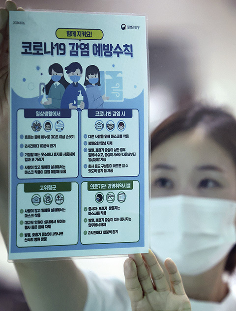 코로나19 환자가 증가하는 가운데 지난 20일 대구 달서구보건소에서 감염병대응팀 직원이 코로나19 감염 예방수칙 홍보물을 부착하고 있다.
