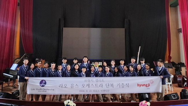 지난달 26일 라오스 비엔티안에서 열린 ‘제32회 아세안 사회문화장관회의’ 폐막 무대를 앞두고 ‘라오 유스오케스트라’ 단원들이 형지엘리트가 후원한 단복을 입고 기념 사진을 촬영하고 있다.(사진= 형지엘리트 제공)