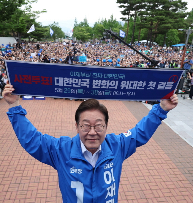 이재명 더불어민주당 대선후보가 지난 22일 경남 양산시 양산워터파크공원에서 열린 집중유세에서 사전투표 독려 현수막을 전달 받은 뒤 들어보이고 있다. 