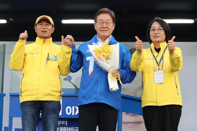 이재명 더불어민주당 대선 후보가 24일 경기 안산 단원구 안산문화광장에서 열린 유세에서 세월호 유가족에게 꽃을 선물받고 함께 시민들에게 인사하고 있다.(사진=뉴시스 제공)
