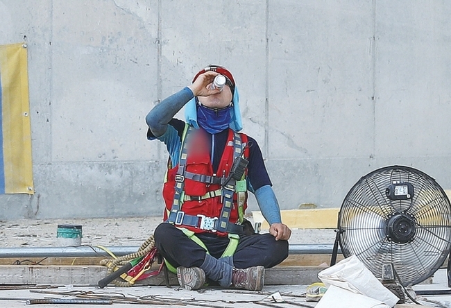한 건설 현장에서 건설 노동자가 그늘에서 휴식을 취하고 있다.