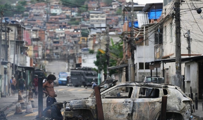 브라질 경찰이 지난 10월 28일 리우데자네이루 시내 빈민가에서 대규모 범죄조직 검거작전을 실시한 뒤  바리케이트로 사용됐던 불탄 차량에서 사람들이 쓸만한 부품을 빼내고 있다.(사진=뉴시스 제공)